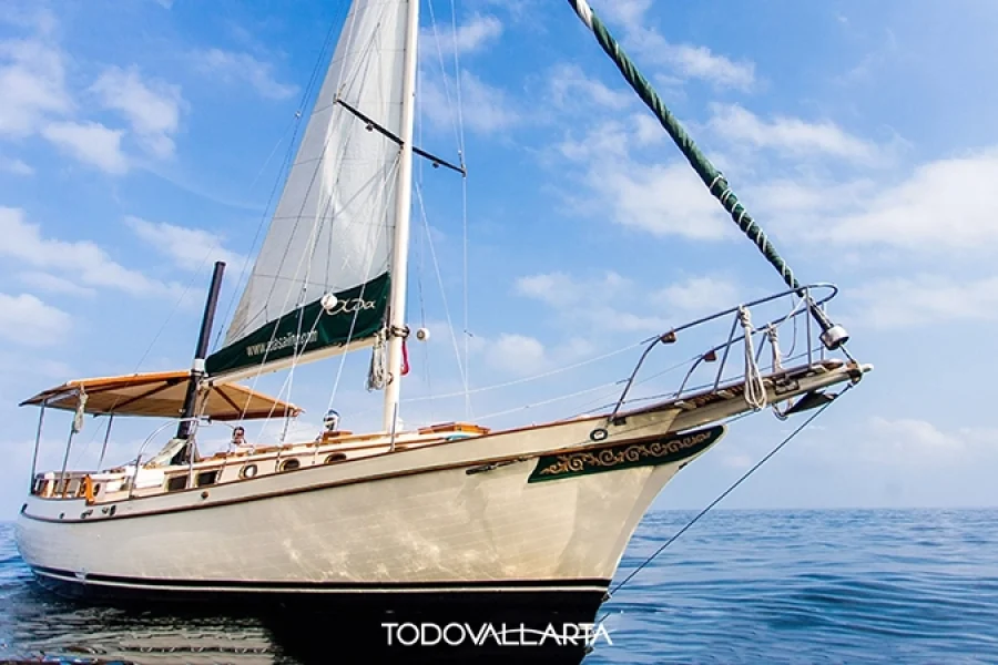 Close-up side view of sailboat Ada in Puerto Vallarta, white sails and blue sky