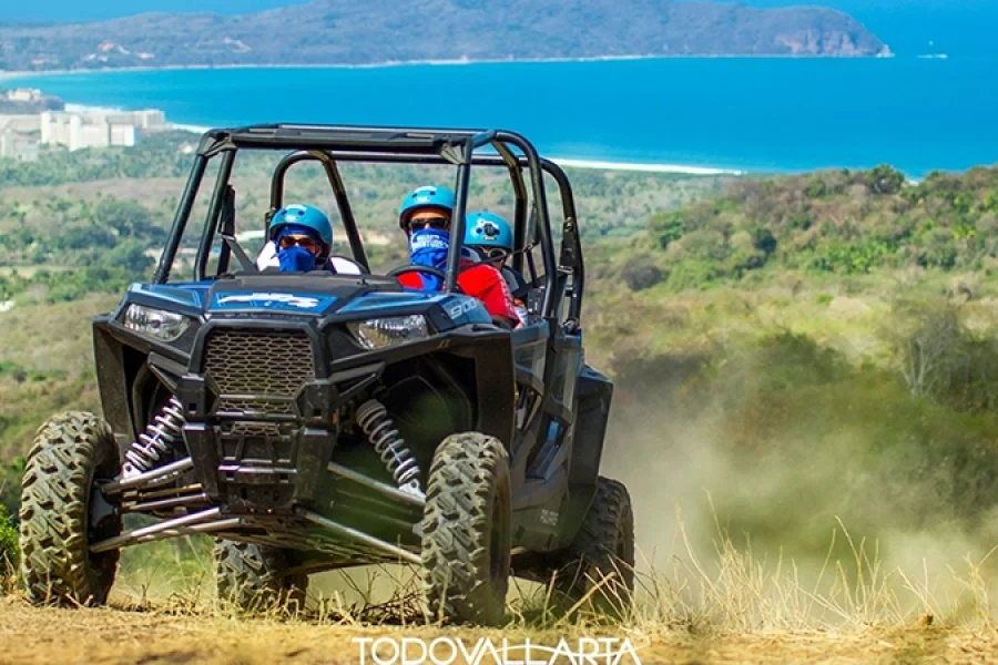 Polaris RZR racing along dirt trail with coastal views