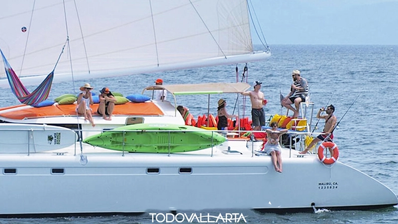 Guests enjoying cocktails and shade on Ally Cat’s aft deck with kayaks and life jackets stowed for catamaran charter 56.