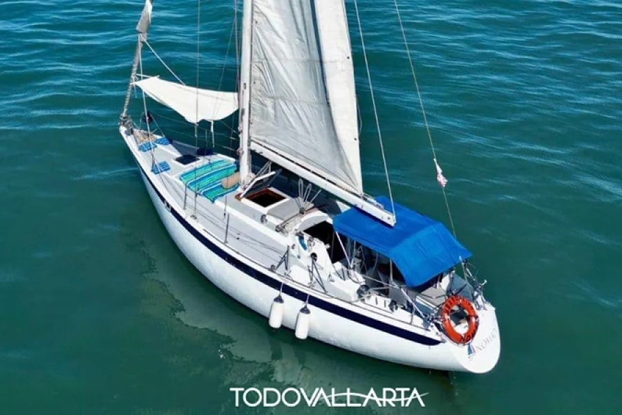 Aerial view of the Nomaad sailboat's port side with its sail raised, navigating the waters of Puerto Vallarta.