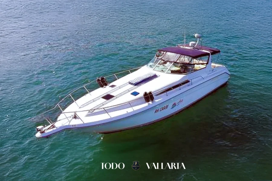 The boat rental searay 42-foot Ah Caray yacht cruising the calm waters of Puerto Vallarta with a clear view of the shoreline.