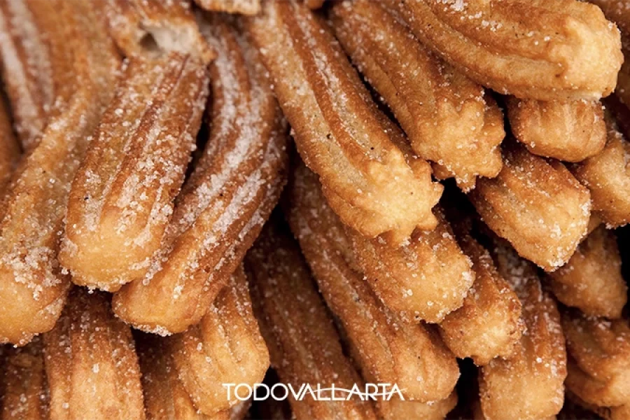 Golden churros coated in sugar, served with Mexican hot chocolate in Puerto Vallarta.
