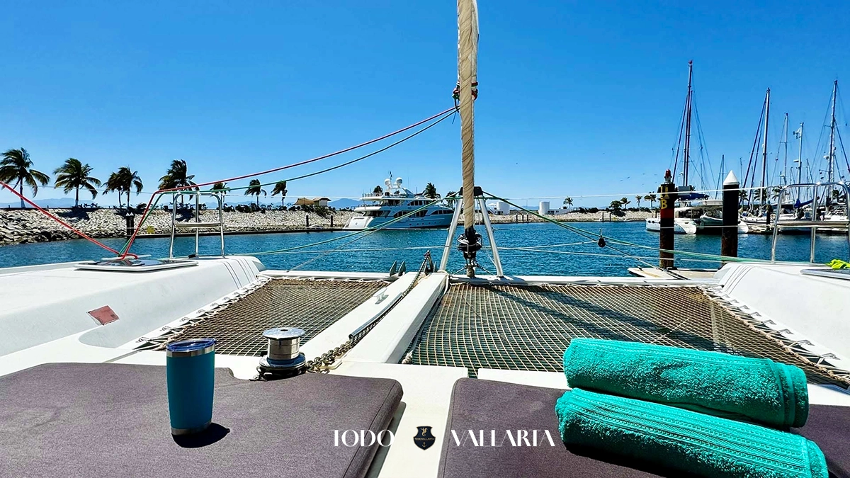 charter goa - 42Ft luxury catamaran forward sun pad with rolled turquoise towels and tumbler by the netted trampoline $